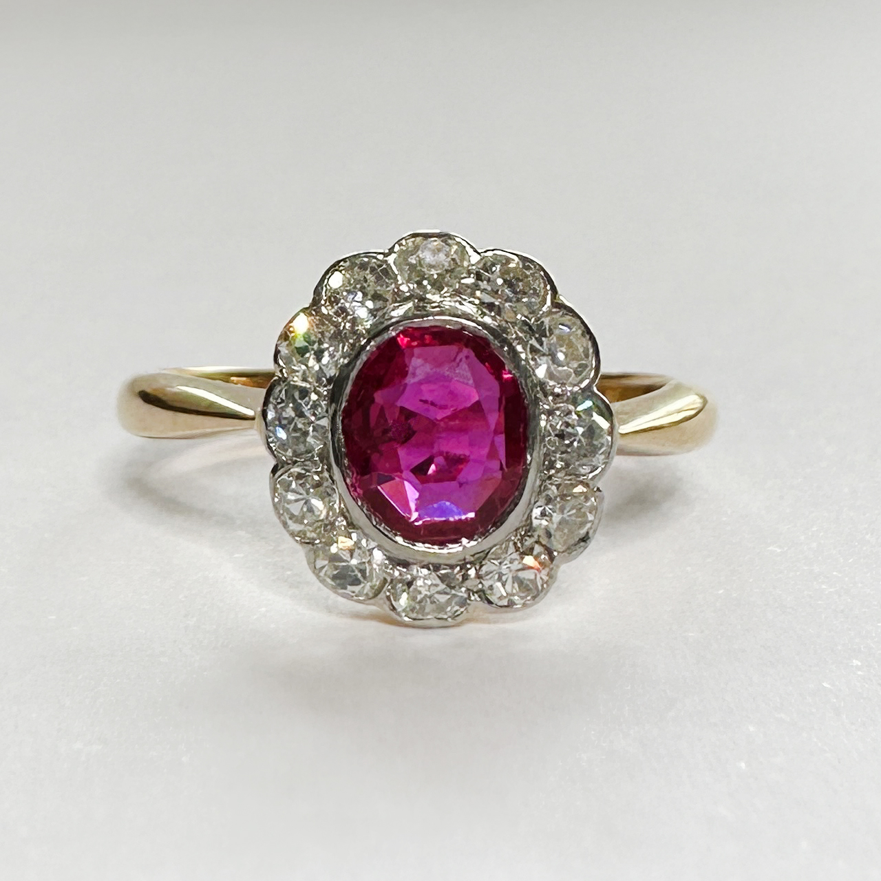 Antique Burma Ruby and Diamond Oval Cluster Ring in 18ct  yellow gold shank, the gems are set in platinum. This exquisite ring has a central natural, unheated Burma ruby and is surrounded by 12 Edwardian bright eight cut diamonds with a total carat weight of 0.50cts. 