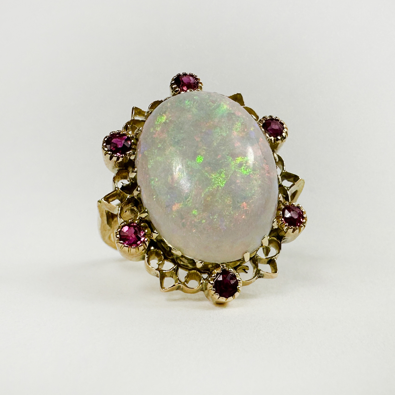 Stunning and Vibrant Large Opal and Ruby Statement Ring.  The opal has striking flashes of green and pink an is encircled by old cut rubies in a rub over setting. Set in 18 carat yellow gold.
