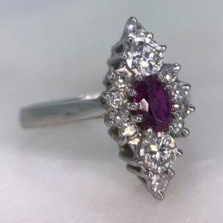 Exquisite Ruby and Diamond Marquise Cluster Ring, in 18ct White Gold Hallmarked, Birmingham (1988). Decorated with a central raspberry pink ruby measuring approximately 5.5 mm x 3.75 mm. The ruby is enclosed by diamonds of two diameters, 2 x 4mm and 10 x 1.5mm. The cluster measures approximately 9 mm x 17.5 mm, all stones are claw set in a polished shank. This ring is in excellent condition. 